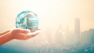 Hands holding globe wearing mask