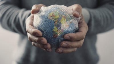 Man holding globe wrapped in bubble wrap