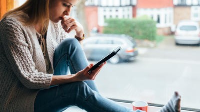 Stressed woman using tablet browsing travel insurance