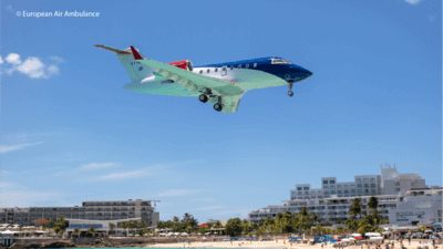 Air ambulance travelling over a beach