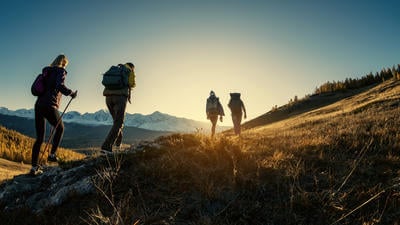 Group of hikers walks in mountains at sunset