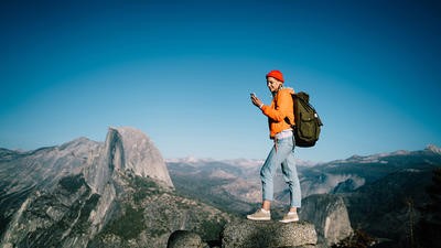 Woman hiking on a mountain and using her phone 