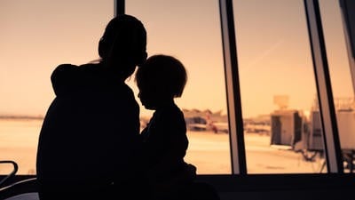 A mother and child looking out of the window of an airport