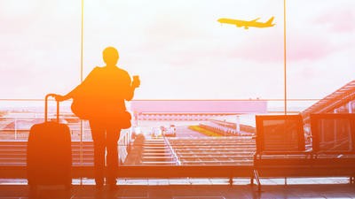 Woman looking out of an airport window, looking at a plane taking off