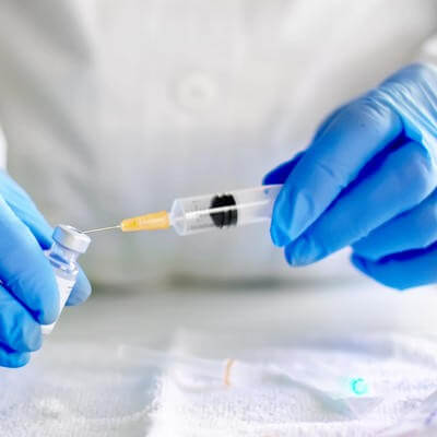 Doctor filling syringe with vaccine