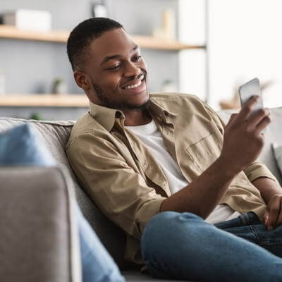 Man sitting on sofa using phone
