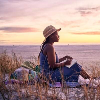 traveller sitting on beach at sunset