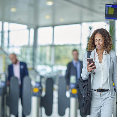Image of a passenger on their phone with suitcase in the background