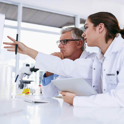 Image of two colleagues in a science lab discussing something on a board