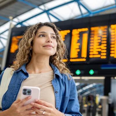 Image of woman at airport with flight timetable behind her