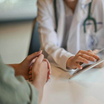 Image of woman talking to doctor with tablet in hand