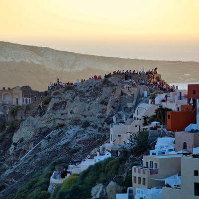 Tourists waiting to see the sunset from ancient fortress in Oia city, Santorini, Greece