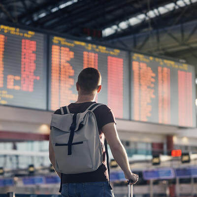 Man walking with backpack and suitcase walking through airport terminal