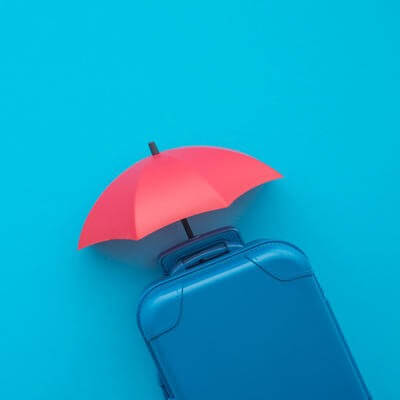 Red umbrella cover suitcases travelers on blue background copy space