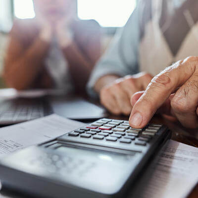 Close up of unrecognizable man calculating home finances while using calculator