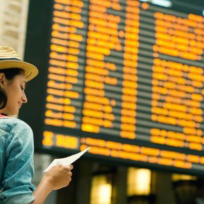 Young woman checking her flight on time board