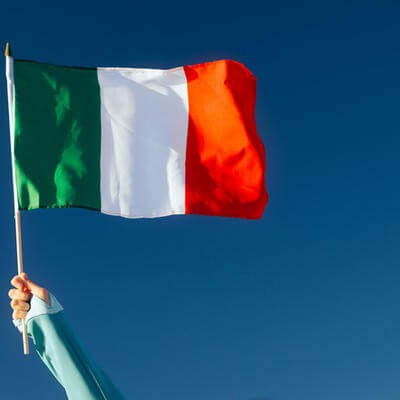 Hand Waiving an Italian Flag on a Blue Sky