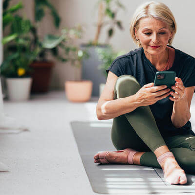Senior Woman Checking Smartphone After Yoga Session at Home