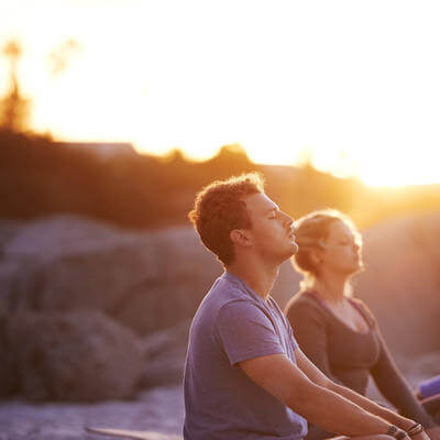 Shot of a group of people practising yoga on the beach