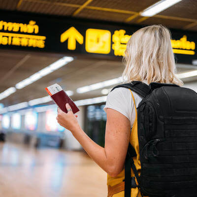A woman at the airport holding a passport with a boarding pass