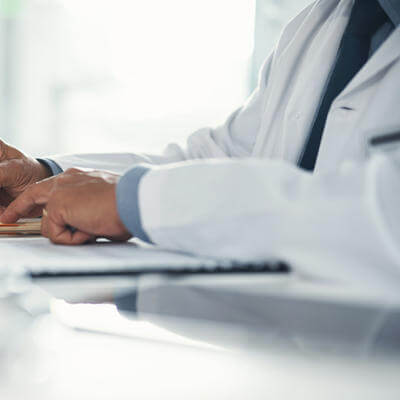 Doctor hands writing on paper or document at a desk in the hospital
