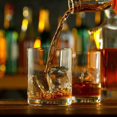 Close-up of pouring whiskey or rum on the bar