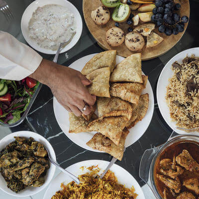 A high-angle shot of an array of curry, rice and other snacks on a dining table, signifying the Eid feast