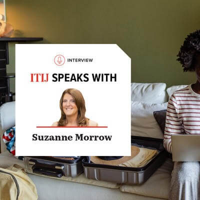 Woman using laptop next to her suitcase