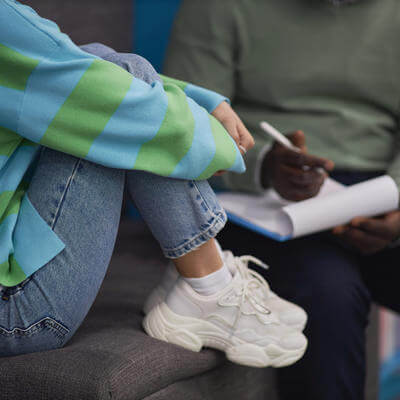 Closeup of stressed teenage girl talking to therapist in session 