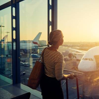 Shot of a young woman looking through the window of an airport departure lounge
