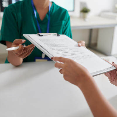 Patient giving filled questionnaire to medical nurse