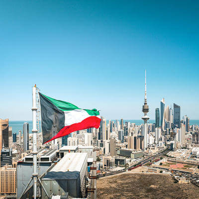 Kuwait flag waving in the wind over the Kuwait City cityscape