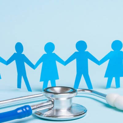 Family doctor. Paper man and woman hold hands on stethoscope background