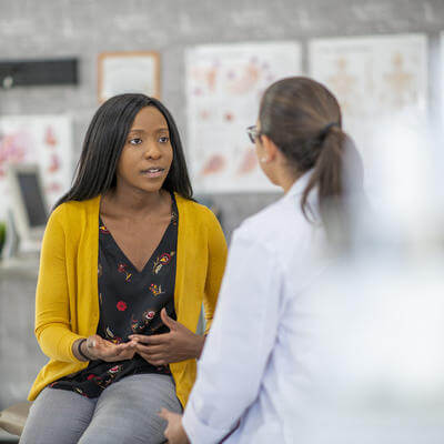 woman is sitting and describing her symptoms to the doctor