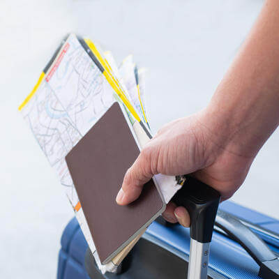 Traveler man holding passports, map for travel with luggage for the trip, copy space for text