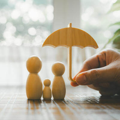 Parent and child model holding an umbrella on a wooden table, concept of health insurance, life and savings insurance
