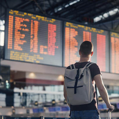 Man walking with backpack and suitcase walking through airport terminal 