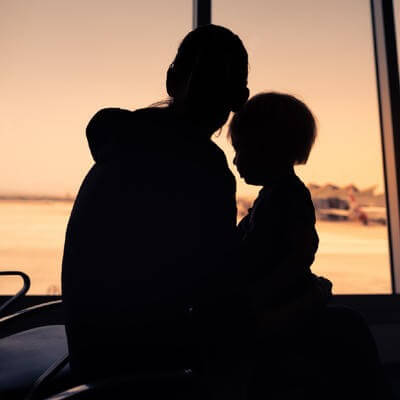 A mother and child looking out of the window of an airport