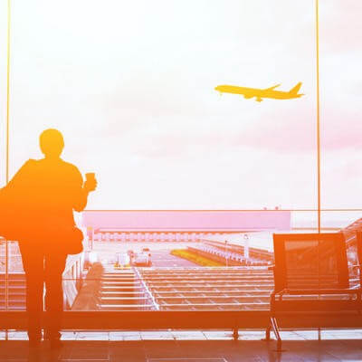 Woman looking out of an airport window, looking at a plane taking off