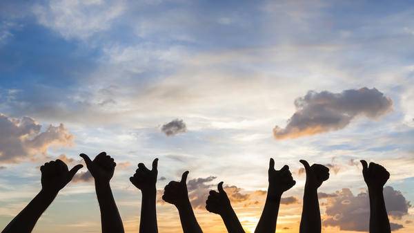 Happy travellers raising their thumbs to the sky