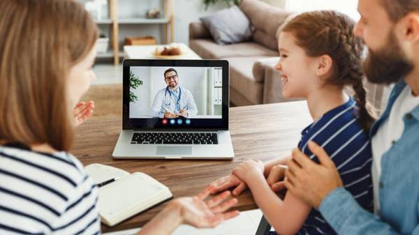 A family talks to a healthcare professional via their laptop