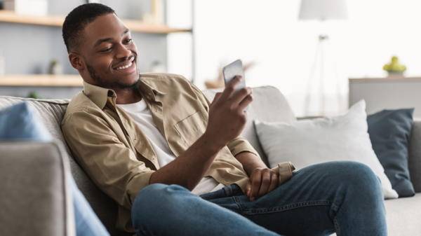 Man sitting on sofa using phone