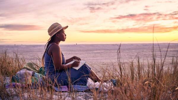 traveller sitting on beach at sunset