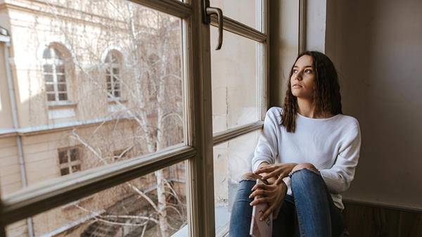 Person looking out of a window in their room