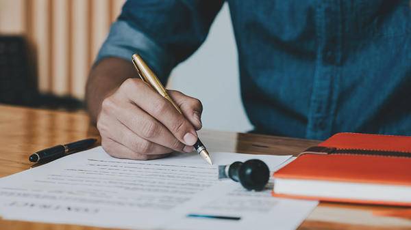 Close up of hands writing legal document 