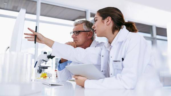 Image of two colleagues in a science lab discussing something on a board