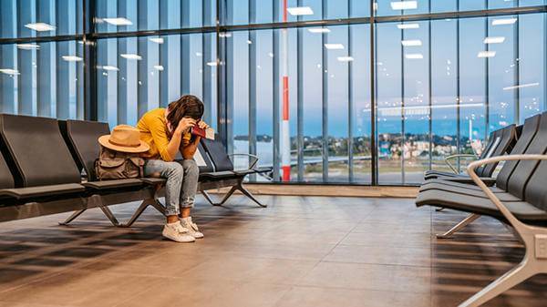 Person in airport with head in hands 
