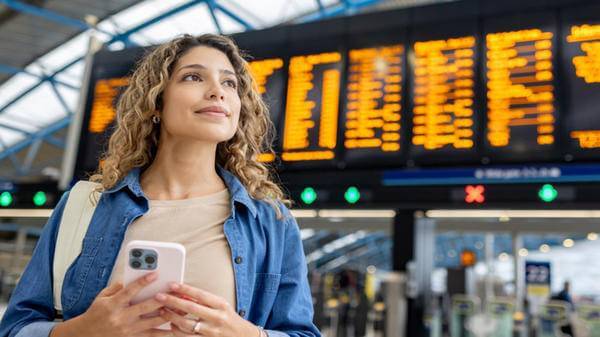 Image of woman at airport with flight timetable behind her