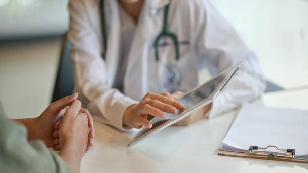 Image of woman talking to doctor with tablet in hand