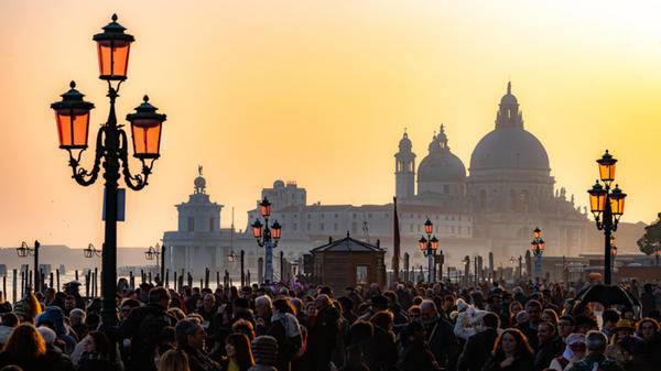 Image of crowds at the carnival in St. Mark's Square, in the background the Basilica of Santa Maria della Salute,Venice, Italy